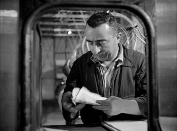 Movie still from “Bicycle Thieves” (1948), directed by Vittorio De Sica – A man looking at a piece of paper in his hands; Medium shot, Low angle