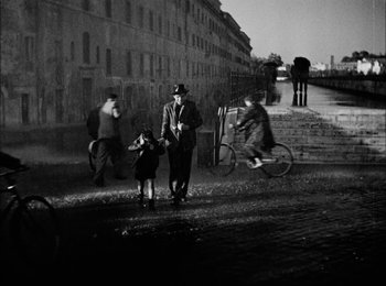 Movie still from “Bicycle Thieves” (1948), directed by Vittorio De Sica – An old black and white photo of people walking down a street; Wide shot, High angle