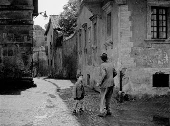 Movie still from “Bicycle Thieves” (1948), directed by Vittorio De Sica – An old photo of a man and a boy walking down the street; Wide shot, Over the shoulder angle