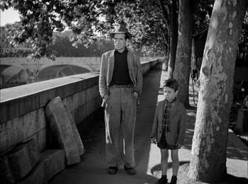 Movie still from “Bicycle Thieves” (1948), directed by Vittorio De Sica – A man and a boy standing next to each other on a sidewalk; Medium shot, High angle