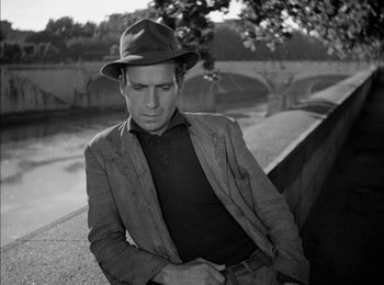 Movie still from “Bicycle Thieves” (1948), directed by Vittorio De Sica – A black and white photo of a man wearing a hat; Medium shot, Low angle