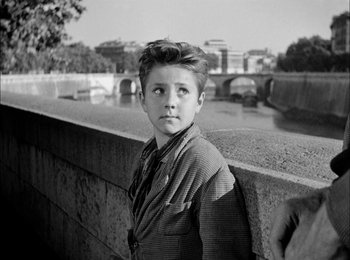 Movie still from “Bicycle Thieves” (1948), directed by Vittorio De Sica – A young boy standing next to a wall; Medium shot, Over the shoulder angle