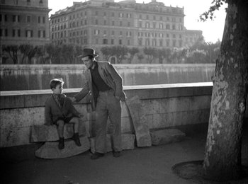 Movie still from “Bicycle Thieves” (1948), directed by Vittorio De Sica – An old photo of a man and a young boy; Wide shot, Over the shoulder angle