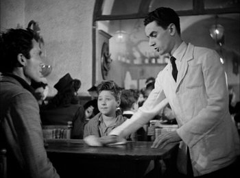 Movie still from “Bicycle Thieves” (1948), directed by Vittorio De Sica – An old photo of a man and a boy at a table; Medium shot, Over the shoulder angle