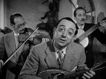 Movie still from “Bicycle Thieves” (1948), directed by Vittorio De Sica – A black - and - white photo of a man holding a guitar; Medium shot, Low angle