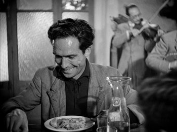 Movie still from “Bicycle Thieves” (1948), directed by Vittorio De Sica – A man sitting at a table with a plate in front of him; Medium shot, Over the shoulder angle