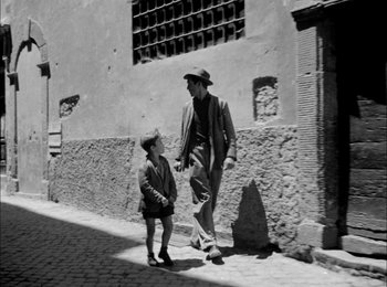 Movie still from “Bicycle Thieves” (1948), directed by Vittorio De Sica – An old photo of a man and a boy walking down the street; Wide shot, Over the shoulder angle