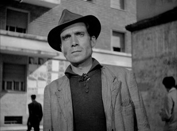 Movie still from “Bicycle Thieves” (1948), directed by Vittorio De Sica – A black and white photo of a man wearing a hat; Medium shot, Low angle
