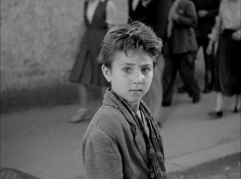 Movie still from “Bicycle Thieves” (1948), directed by Vittorio De Sica – Black and white photograph of a young boy in front of a crowd of onlookers; Medium shot, High angle