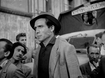 Movie still from “Bicycle Thieves” (1948), directed by Vittorio De Sica – Black and white photograph of a man wearing a hat; Medium shot, Low angle