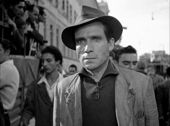 Movie still from “Bicycle Thieves” (1948), directed by Vittorio De Sica – Black and white photograph of a man in a hat; Medium shot, Low angle