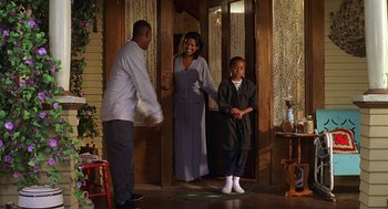 Movie still from “Big Momma's House” (2000), directed by Raja Gosnell – A man , woman , and a child standing in front of an open door; Wide shot, High angle
