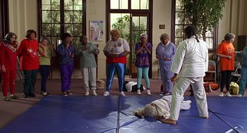 Movie still from “Big Momma's House” (2000), directed by Raja Gosnell – A group of people standing around a person lying on the ground; Wide shot, High angle