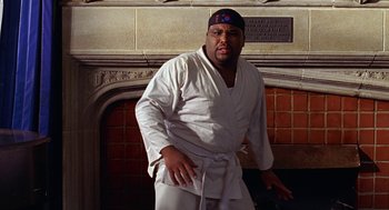 Movie still from “Big Momma's House” (2000), directed by Raja Gosnell – A man in a karate outfit standing in front of a fireplace; Medium shot, Low angle