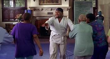 Movie still from “Big Momma's House” (2000), directed by Raja Gosnell – A man in white shirt and white pants holding hands with two other people; Medium shot, Over the shoulder angle