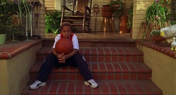 Movie still from “Big Momma's House” (2000), directed by Raja Gosnell – A young boy sitting on the steps holding a basketball; Wide shot, High angle