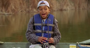 Movie still from “Big Momma's House” (2000), directed by Raja Gosnell – A young boy holding a camera while sitting on a dock; Close Up shot, High angle