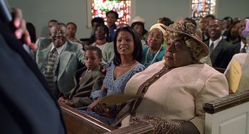 Movie still from “Big Momma's House” (2000), directed by Raja Gosnell – A group of people sitting in front of a stained glass window; Medium shot, Low angle