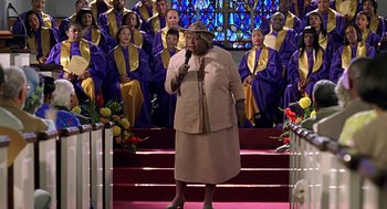 Movie still from “Big Momma's House” (2000), directed by Raja Gosnell – An older woman standing in front of a group of people; Medium shot, High angle