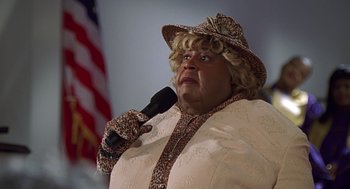 Movie still from “Big Momma's House” (2000), directed by Raja Gosnell – A woman in a brown hat holding a microphone up to her mouth; Close Up shot, Low angle