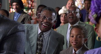 Movie still from “Big Momma's House” (2000), directed by Raja Gosnell – A group of people in suits and ties smiling for the camera; Medium shot, Low angle