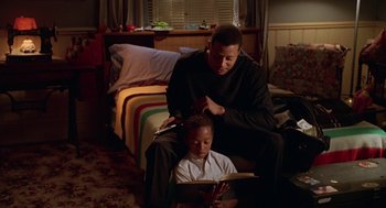 Movie still from “Big Momma's House” (2000), directed by Raja Gosnell – A man sitting next to a young boy reading a book; Medium shot, High angle