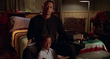 Movie still from “Big Momma's House” (2000), directed by Raja Gosnell – A man sitting next to a child in a living room; Medium shot, High angle