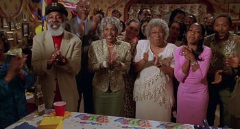 Movie still from “Big Momma's House” (2000), directed by Raja Gosnell – A group of people standing in front of a table; Medium shot, High angle