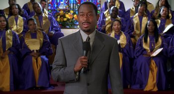 Movie still from “Big Momma's House” (2000), directed by Raja Gosnell – A man is holding a microphone in front of a crowd; Medium shot, High angle