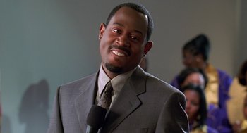 Movie still from “Big Momma's House” (2000), directed by Raja Gosnell – A man wearing a suit and tie smiling for the camera; Close Up shot, Low angle