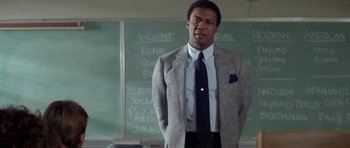 Movie still from “Bill & Ted's Excellent Adventure” (1989), directed by Stephen Herek – A man standing in front of a chalkboard in front of a blackboard; Medium shot, Low angle