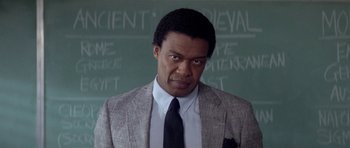 Movie still from “Bill & Ted's Excellent Adventure” (1989), directed by Stephen Herek – A man in a suit and tie in front of a chalkboard; Close Up shot, Low angle