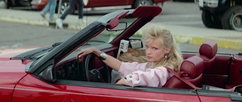 Movie still from “Bill & Ted's Excellent Adventure” (1989), directed by Stephen Herek – A woman sitting in the driver's seat of a red car; Medium shot, Low angle