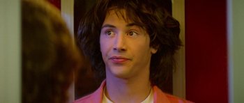 Movie still from “Bill & Ted's Excellent Adventure” (1989), directed by Stephen Herek – A young man with long hair is looking into the distance; Close Up shot, Over the shoulder angle