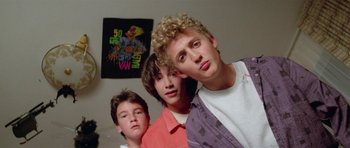 Movie still from “Bill & Ted's Excellent Adventure” (1989), directed by Stephen Herek – Three young men posing for a picture in front of a wall; Medium shot, Low angle