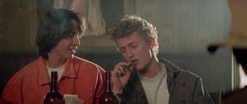 Movie still from “Bill & Ted's Excellent Adventure” (1989), directed by Stephen Herek – A man talking on a cell phone next to another man; Medium shot, Low angle