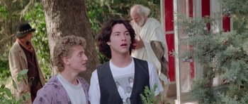 Movie still from “Bill & Ted's Excellent Adventure” (1989), directed by Stephen Herek – A young man standing in front of two other people; Medium shot, Over the shoulder angle