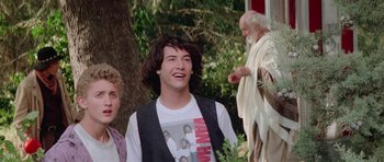 Movie still from “Bill & Ted's Excellent Adventure” (1989), directed by Stephen Herek – A man in a white shirt is standing next to another man in a black vest; Medium shot, Low angle