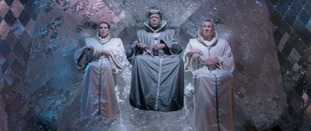 Movie still from “Bill & Ted's Excellent Adventure” (1989), directed by Stephen Herek – A man sitting on top of a glass table surrounded by two women; Wide shot, High angle