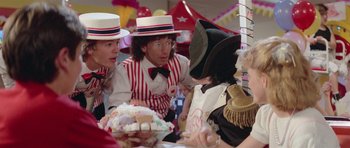 Movie still from “Bill & Ted's Excellent Adventure” (1989), directed by Stephen Herek – A group of people sitting at a table wearing hats; Medium shot, Over the shoulder angle