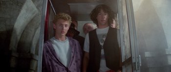 Movie still from “Bill & Ted's Excellent Adventure” (1989), directed by Stephen Herek – A group of young men standing next to each other on a train; Medium shot, Low angle