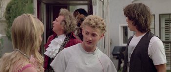 Movie still from “Bill & Ted's Excellent Adventure” (1989), directed by Stephen Herek – A young man with blonde hair is listening to music while another man with blonde hair looks on; Medium shot, Over the shoulder angle