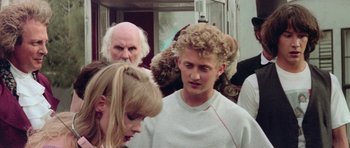 Movie still from “Bill & Ted's Excellent Adventure” (1989), directed by Stephen Herek – A group of people standing next to each other on a street; Medium shot, Over the shoulder angle
