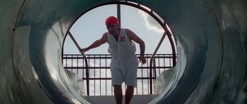Movie still from “Bill & Ted's Excellent Adventure” (1989), directed by Stephen Herek – A man with a red hat is on a slide; Medium shot, Low angle