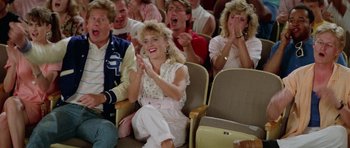 Movie still from “Bill & Ted's Excellent Adventure” (1989), directed by Stephen Herek – A group of people sitting and clapping in a room; Medium shot, High angle