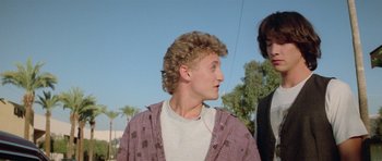 Movie still from “Bill & Ted's Excellent Adventure” (1989), directed by Stephen Herek – A young man wearing a jacket and headphones in a park; Close Up shot, Low angle