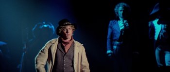 Movie still from “Bill & Ted's Excellent Adventure” (1989), directed by Stephen Herek – A man wearing a hat standing in front of a projection screen; Medium shot, Low angle