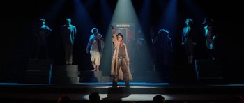 Movie still from “Bill & Ted's Excellent Adventure” (1989), directed by Stephen Herek – A man is standing on a stage with a microphone; Wide shot, Low angle