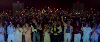 Movie still from “Bill & Ted's Excellent Adventure” (1989), directed by Stephen Herek – A group of people are gathered in a theater holding lit candles; Wide shot, High angle