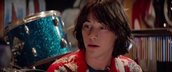 Movie still from “Bill & Ted's Excellent Adventure” (1989), directed by Stephen Herek – A young man with long brown hair wearing a floral shirt; Close Up shot, Over the shoulder angle